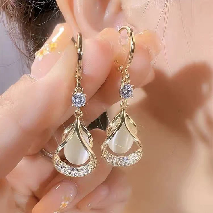 Three pairs of WIMAID™ Lymph Flow Magnetogen Earrings in white, blue, and purple with silver hooks, displayed on a white background.